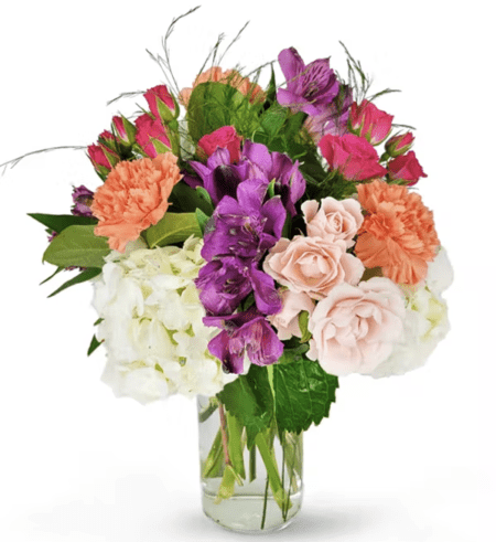 Send a beautiful floral greeting with carnations, alstroemeria, roses, hydrangea, and mixed greens in a clear glass vase. 